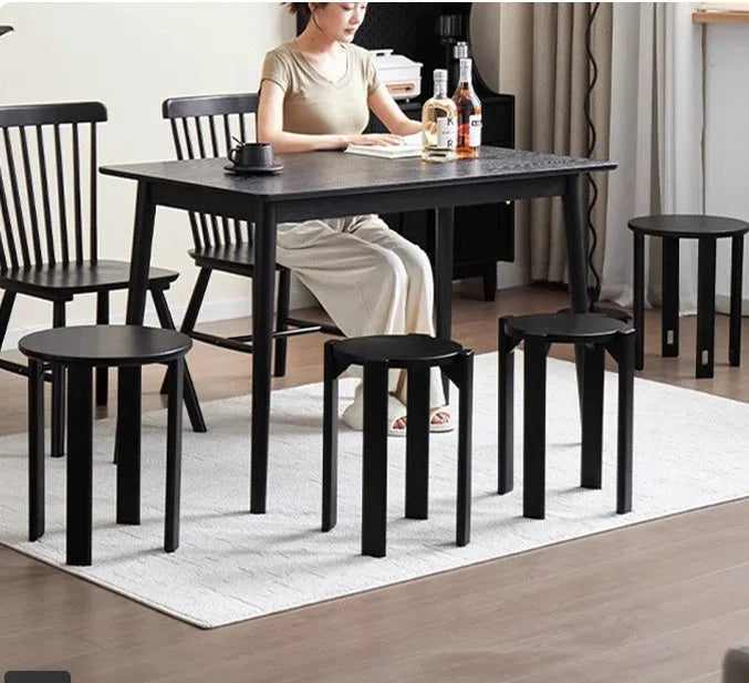 Set of four stackable iron dining stools with circular seats in a modern design, shown nested together.