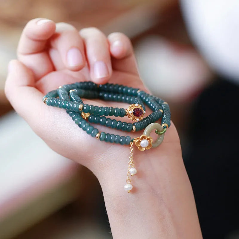 Women's bracelet with small blue water jade abacus beads, tourmaline rings, and pearls on a wrist