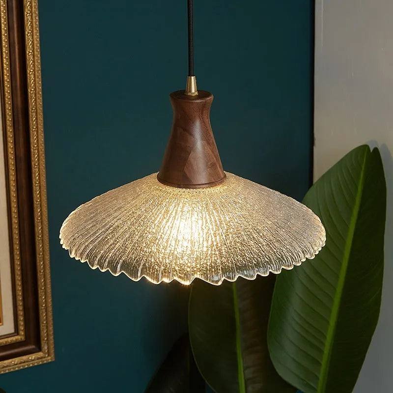 Retro chandelier with wooden body, brass metalwork, and a clear glass shade hanging from the ceiling.