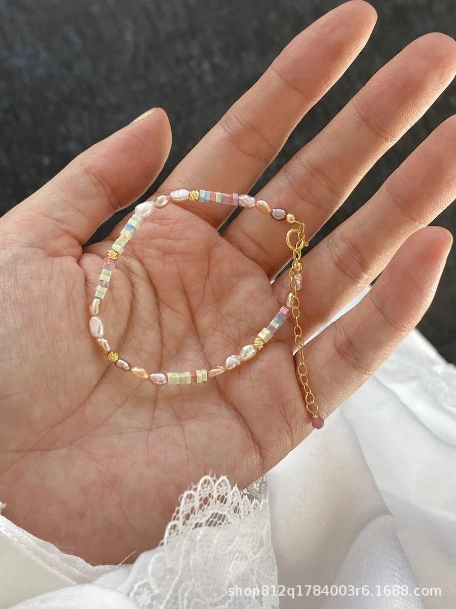Women's natural pearl bracelet and necklace set with a purple and gold-plated clasp on a silver chain.