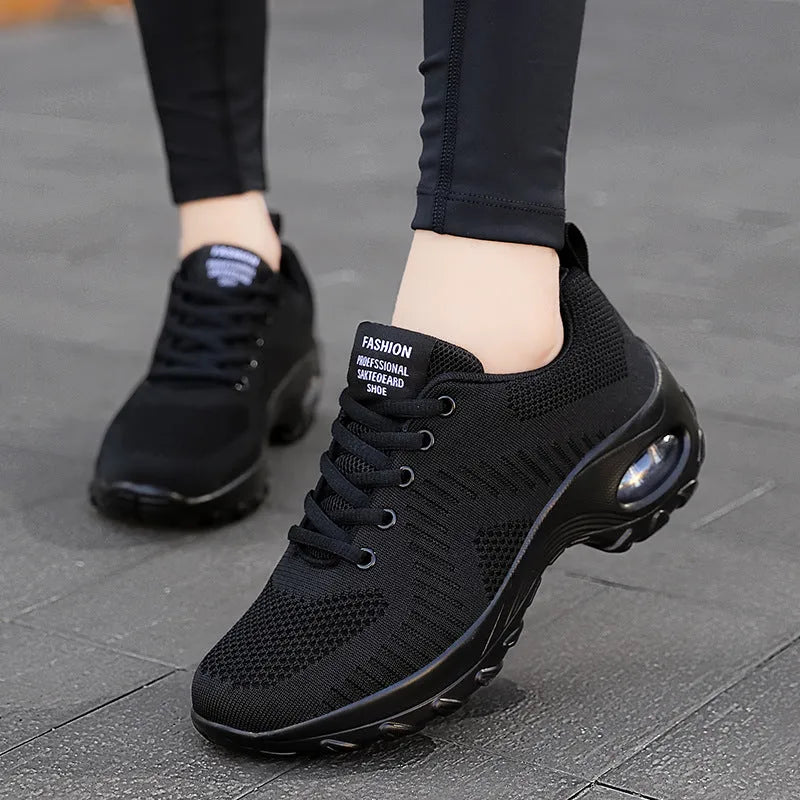 Red and black women's low-top mesh sneakers with front laces and a flat sole on a white background.