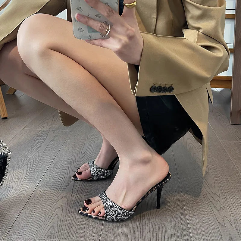 Black women's sandals with pointed stiletto heel, rhinestone details, and oversleeves.