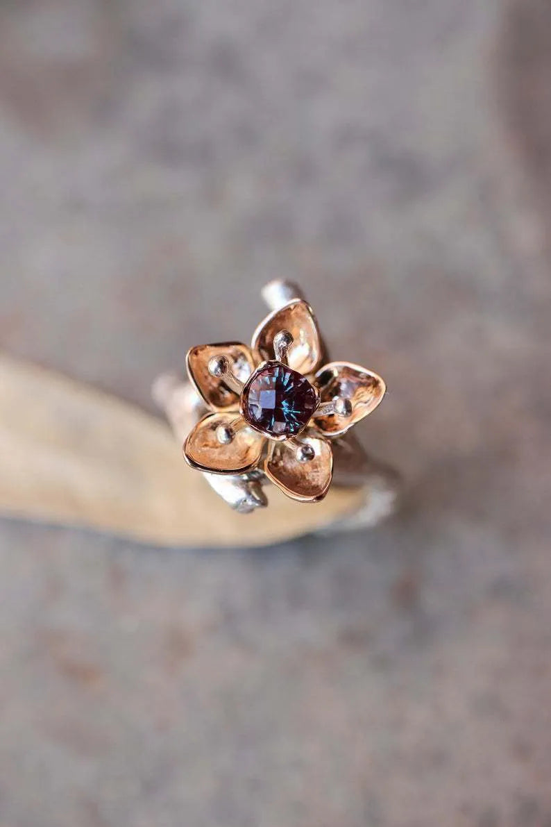 A silver two-tone floral ring with a geometric shape on a model's finger.
