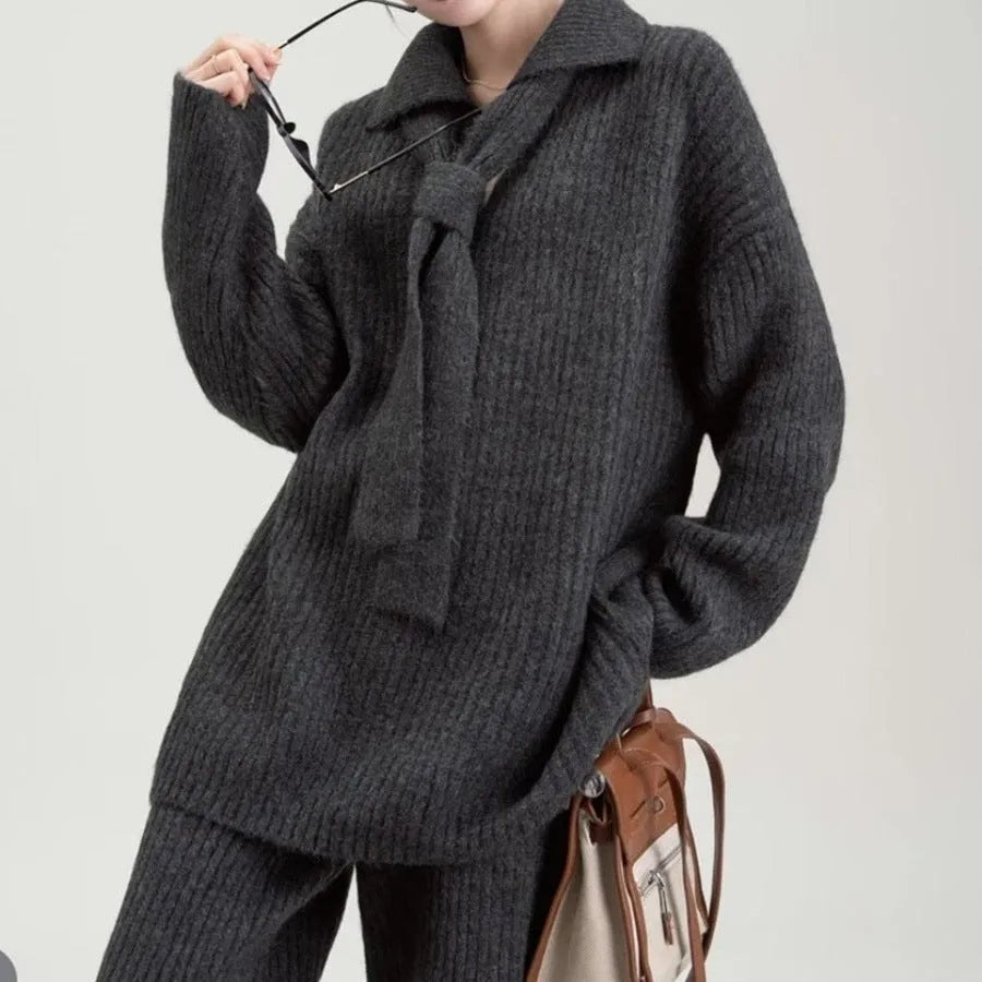 Women's beige knitted two-piece suit set showing V-neck top and straight-leg trousers on a hanger.
