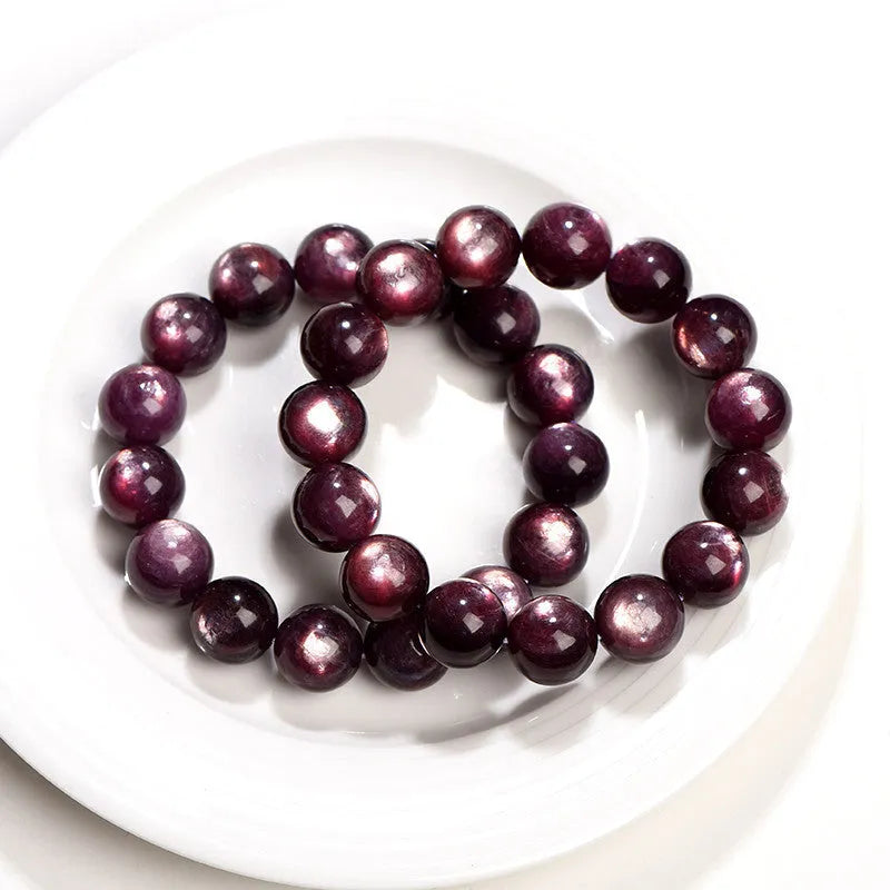 Purple lepidolite crystal round bead bracelet on a wrist, showing polished stones.