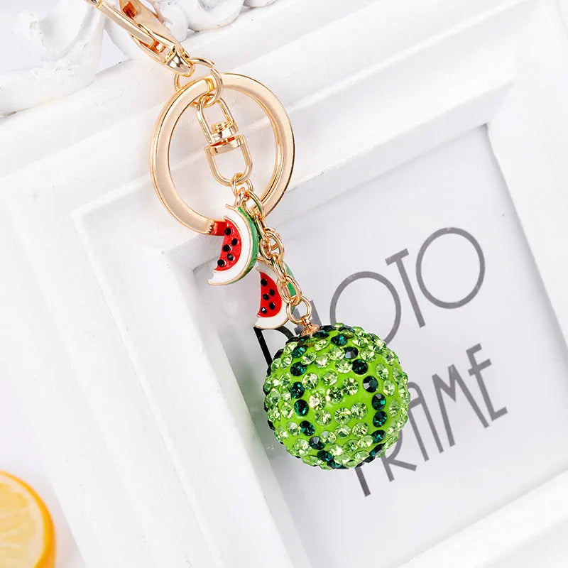 Green watermelon-shaped metal keychain on a white background