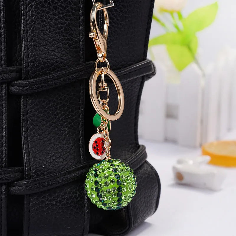 Green watermelon-shaped metal keychain on a white background