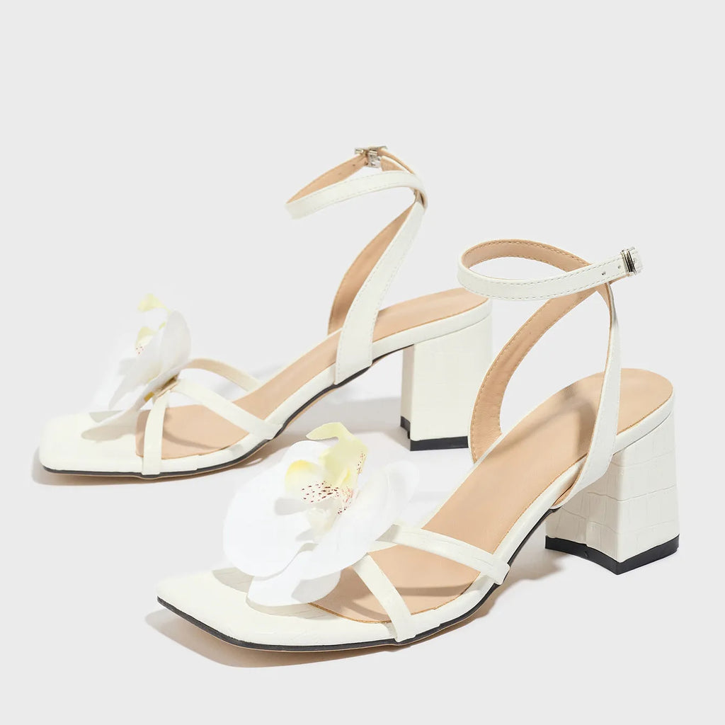 White women's sandals with a square toe, chunky high heel, and three-dimensional flower decorations.