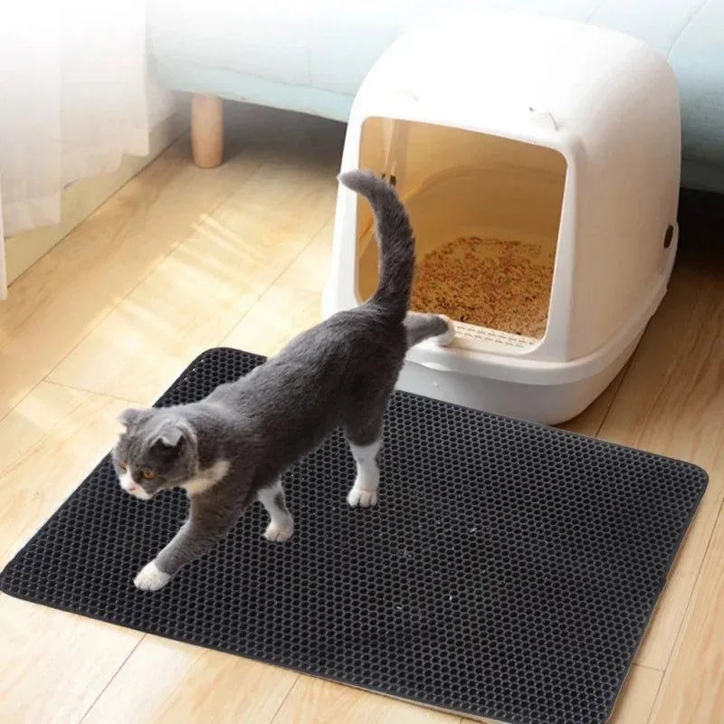Black waterproof EVA cat litter mat with honeycomb surface for trapping litter, shown next to a litter box.