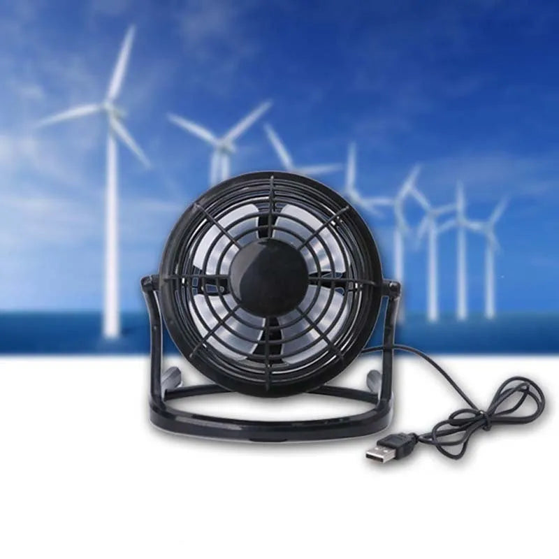Mini adjustable tilt USB desk fan in black, shown on a desk next to a laptop
