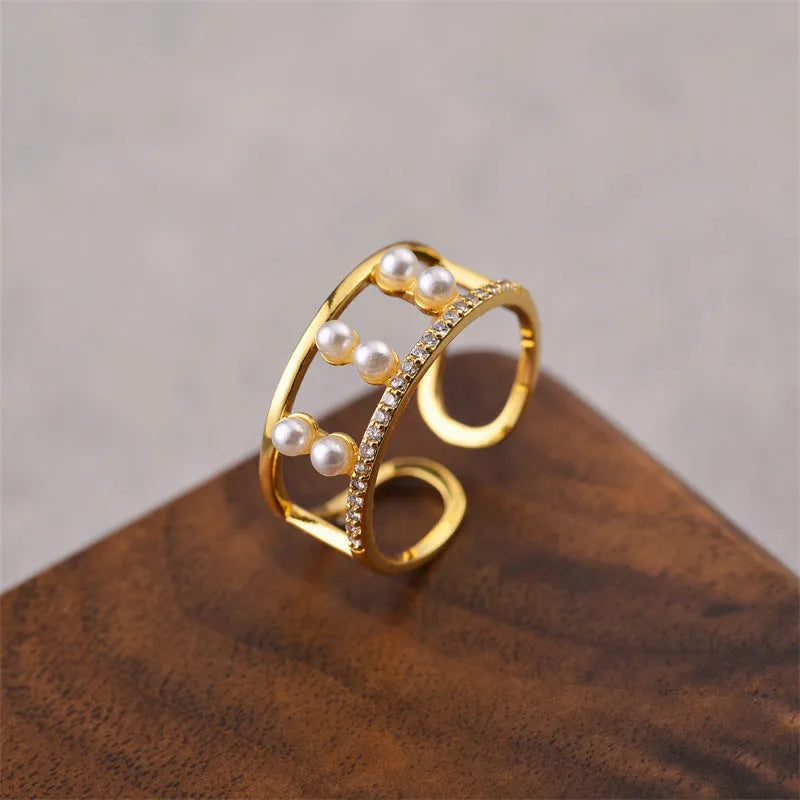 Gold electroplated copper open geometric women's fashion ring on a plain background.