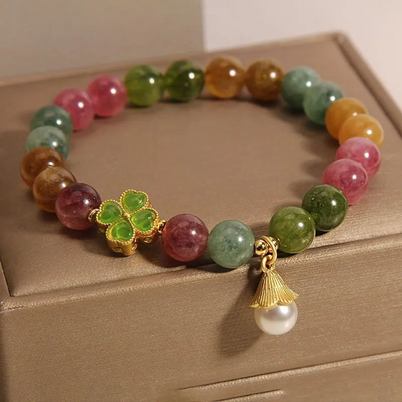 Natural colour tourmaline bracelet with four-leaf clover pearl pendant, geometric drop shape on woman's wrist.