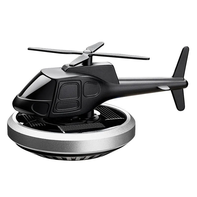 Silver metal solar-powered helicopter car air freshener spinning on a car dashboard