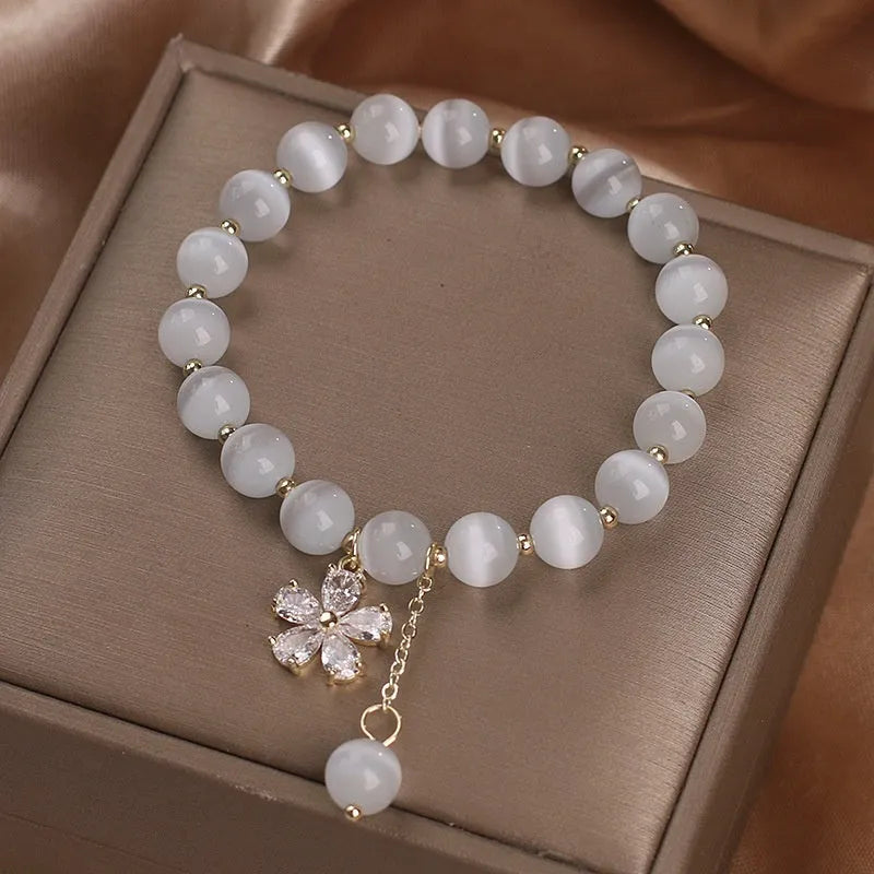 White cats eye crystal bracelet with flower charms, tassels and safety buckle closure