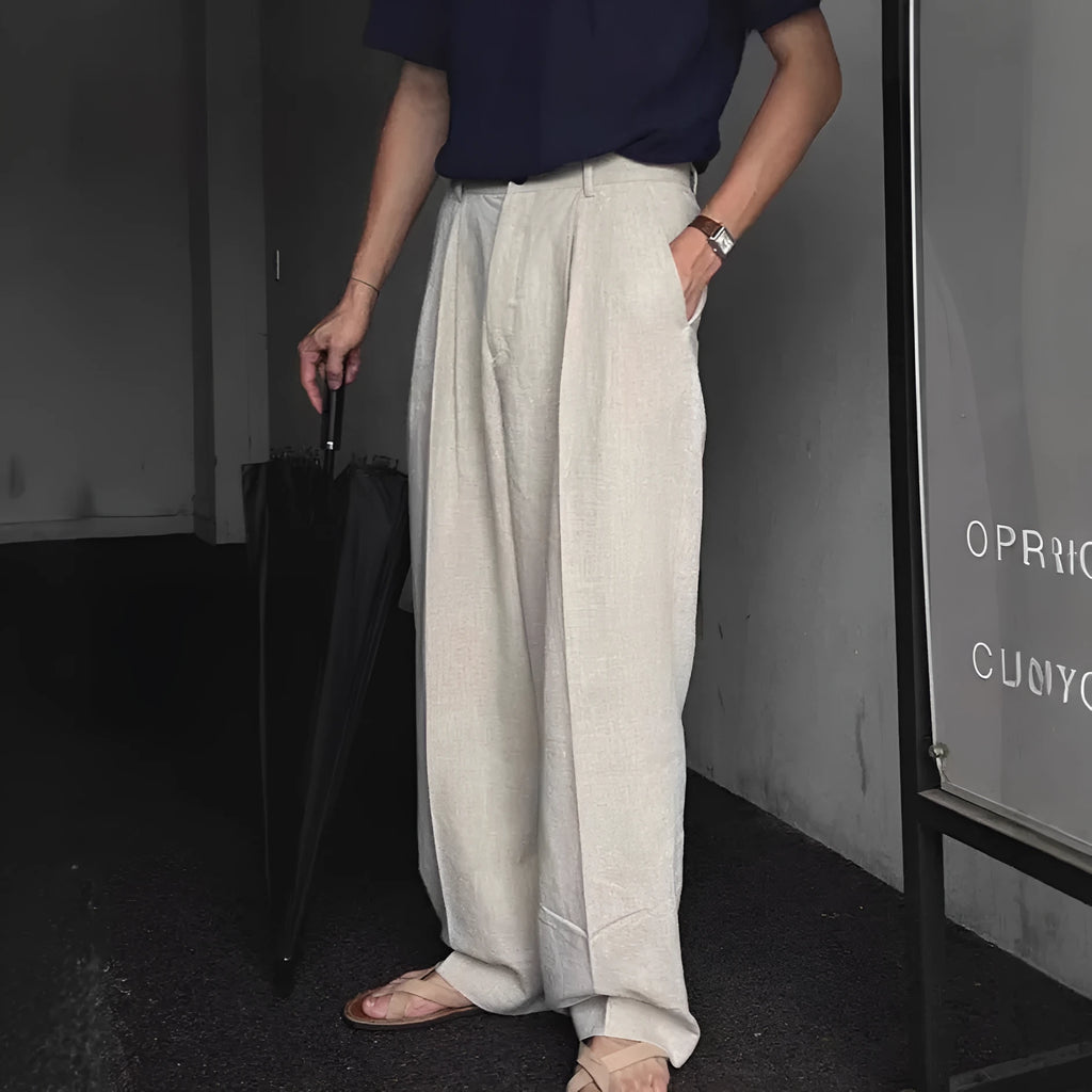 Men's apricot coloured loose-fit cotton linen suit trousers with a pencil leg on a neutral background.