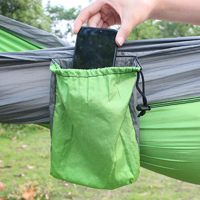 A sapphire blue parachute nylon hammock hung between two trees in a woodland setting.