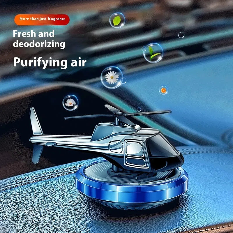 Silver metal solar-powered helicopter car air freshener spinning on a car dashboard