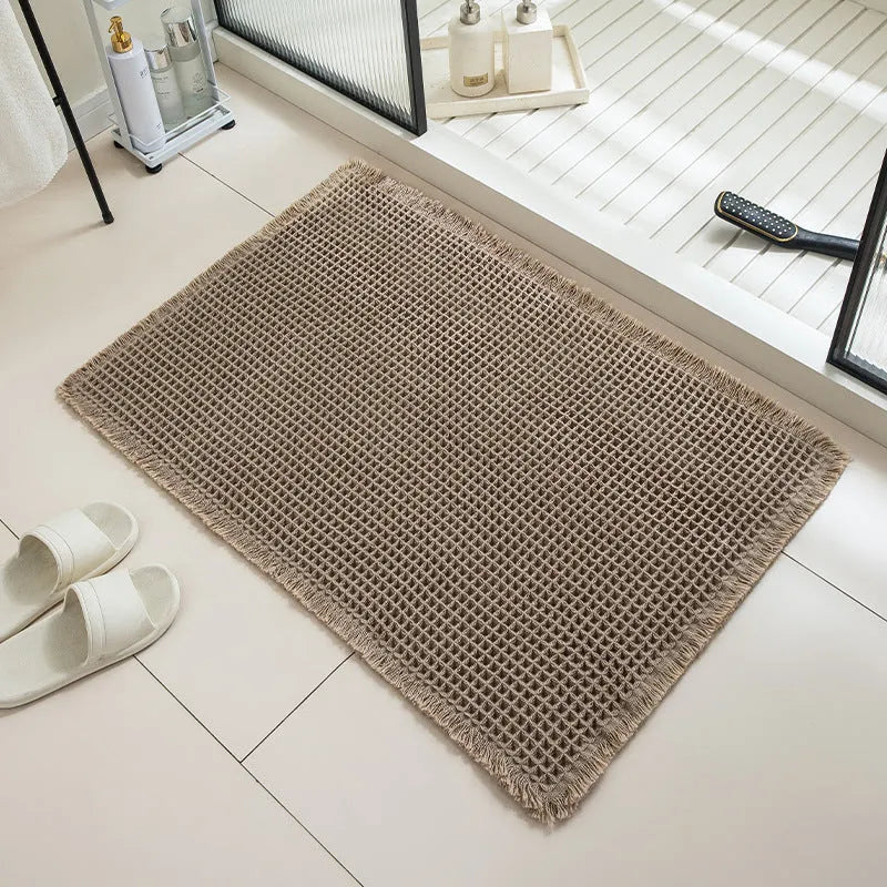 A beige checkered non-slip polyester bathroom carpet on a tiled floor.