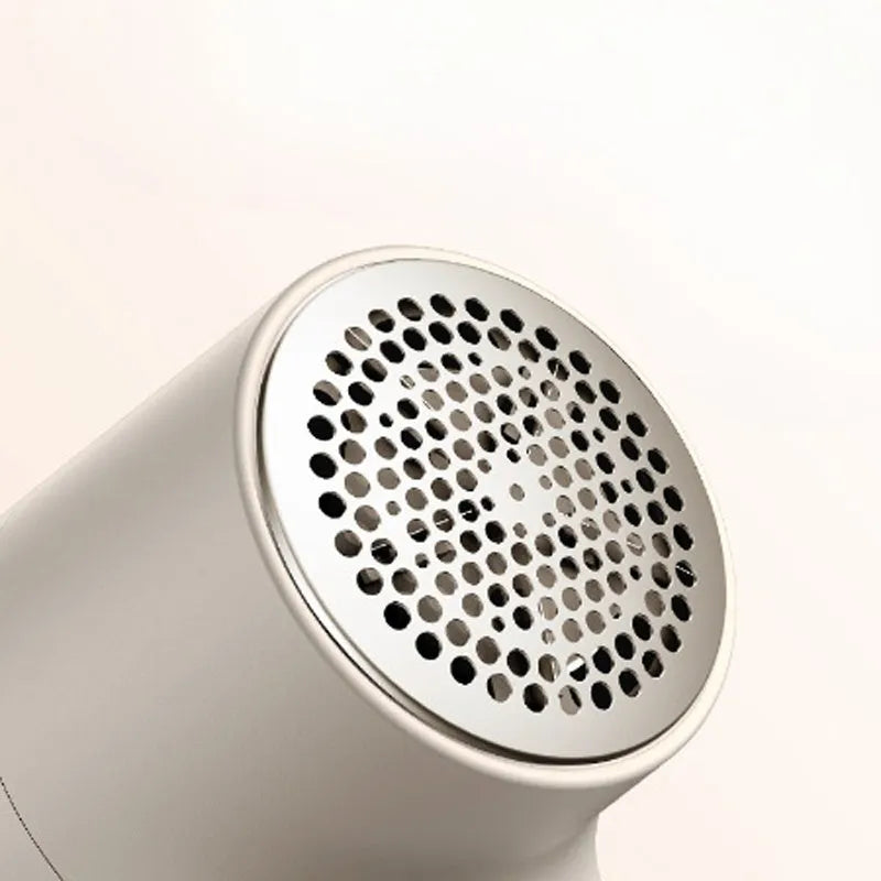 White electric lint remover with LED display and USB charging port on a fabric surface.
