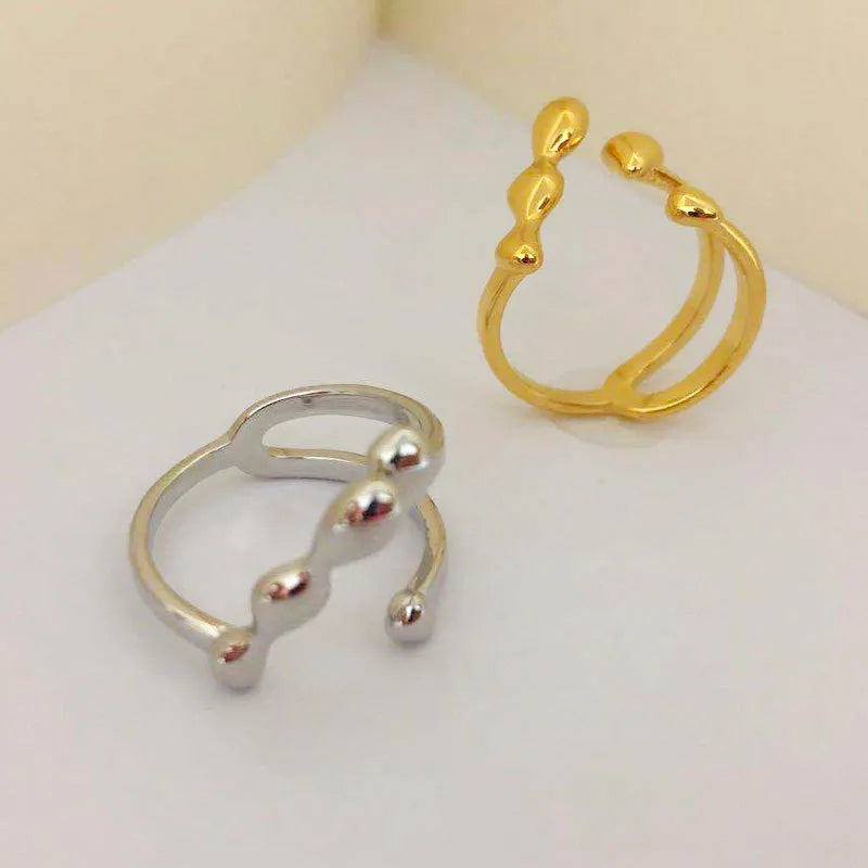 Gold brass opening ring with sphere design on a white background.