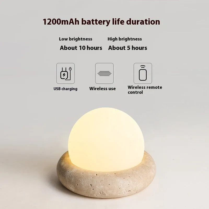 Cream coloured modern bedside night lamp with remote control on a table.