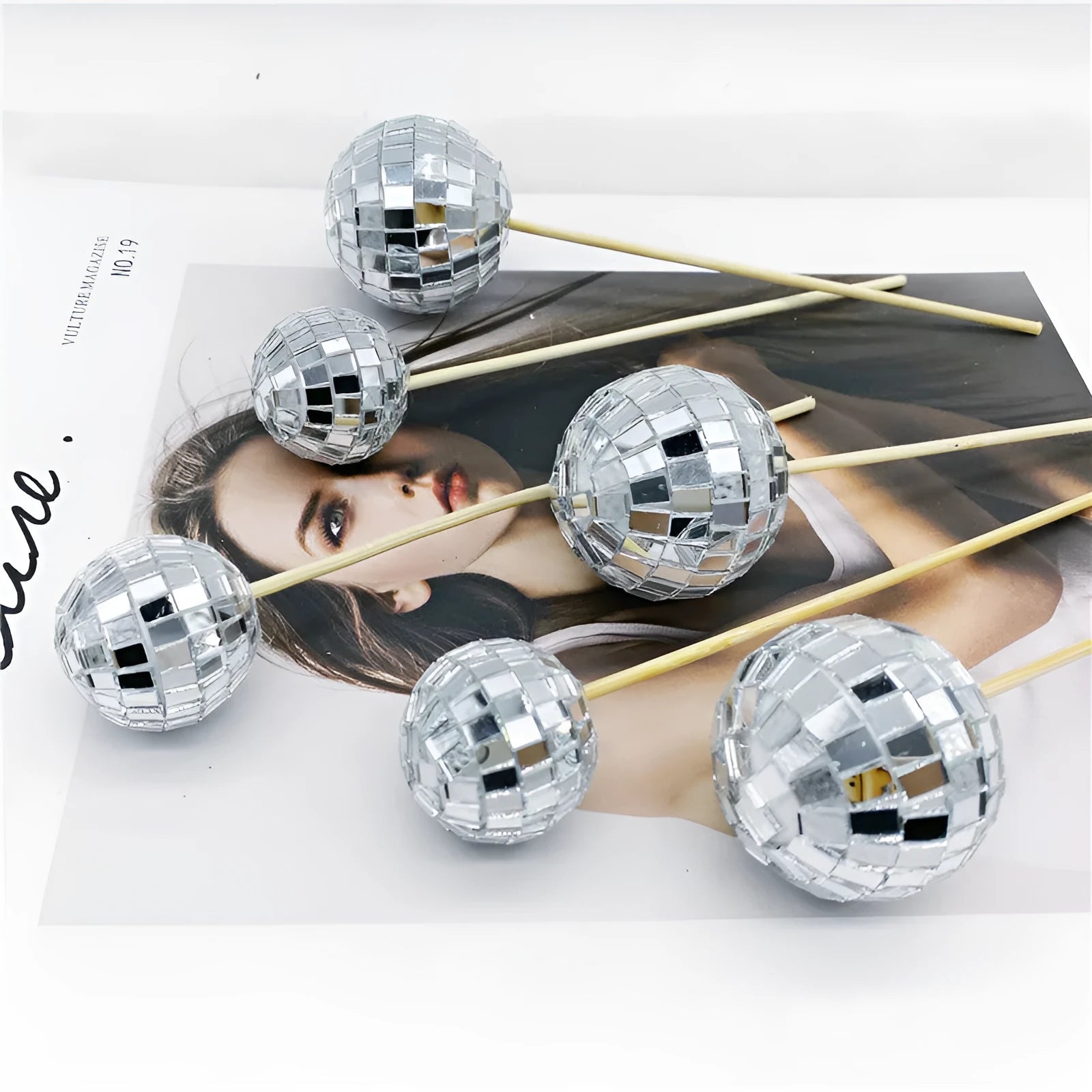 Glass disco ball cake decoration on a wooden stick in various sizes on a cake.