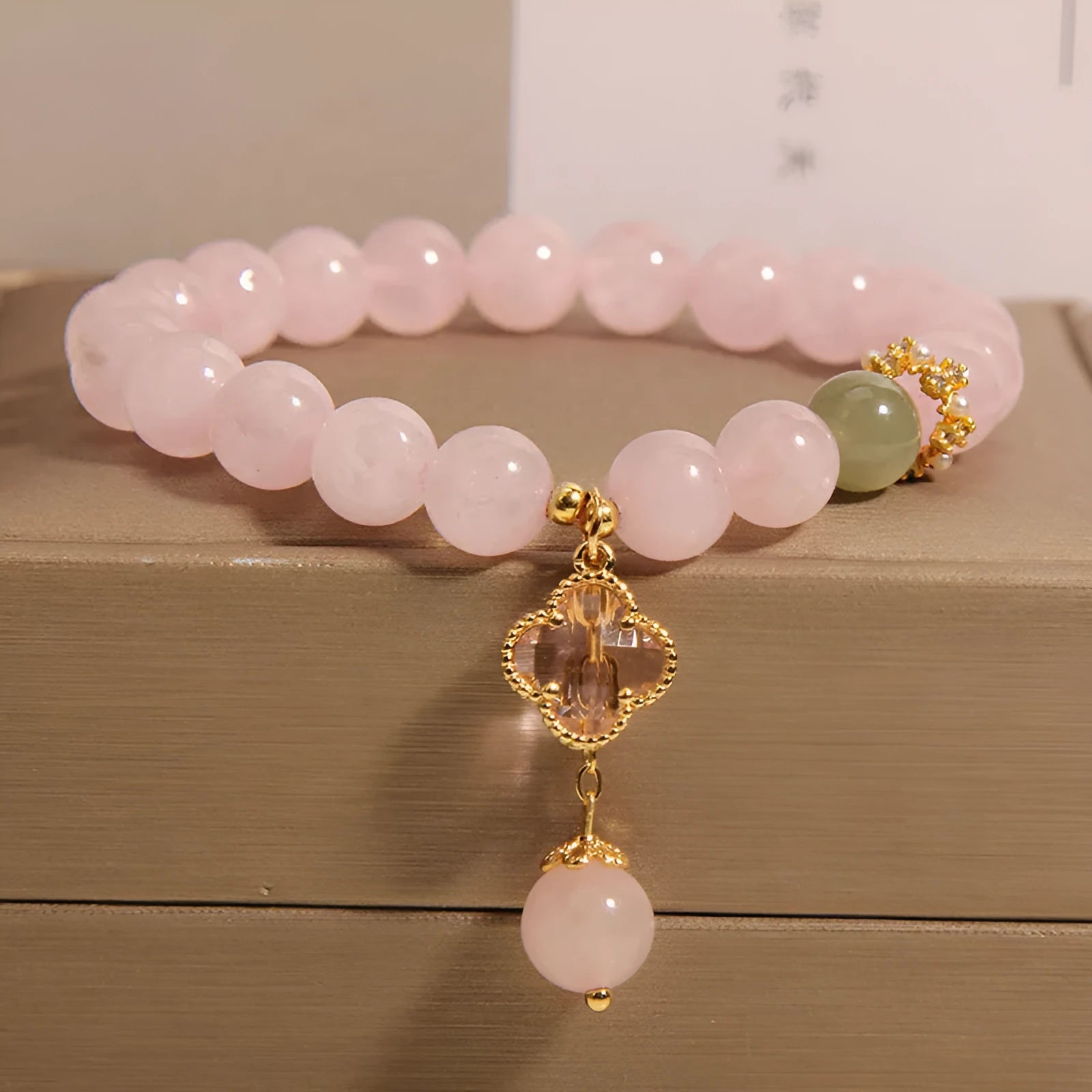 Pink crystal women's bracelet with four-leaf clover pendant charm and rhinestone decoration.
