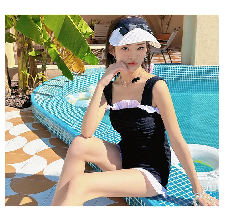 Women's solid colour one-piece jumpsuit swimsuit with suspender straps in pink, green, or black.