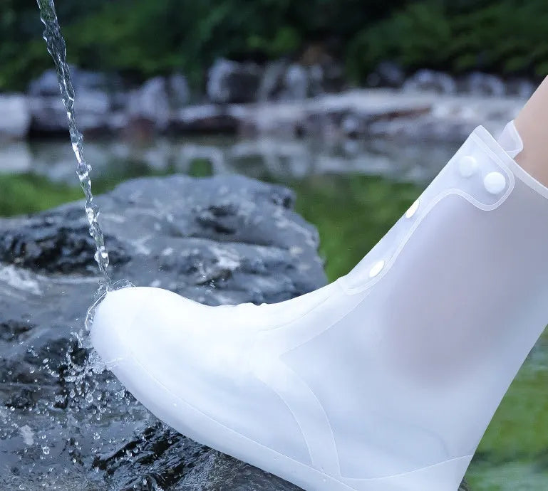 White high-top PVC reusable waterproof shoe covers for women on a wet surface.