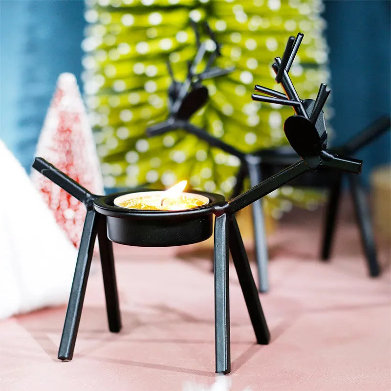 Black iron Christmas deer candlestick holder with elk silhouette on a table.