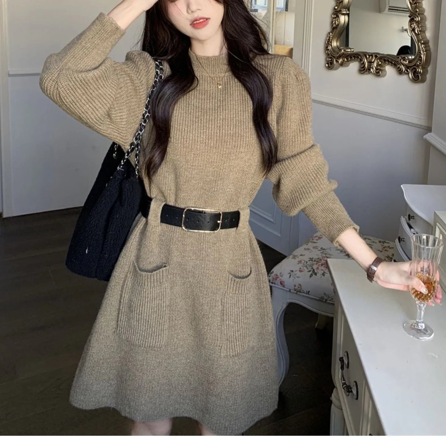 Women's beige loose knitted long sleeve dress with high waist and a black belt.