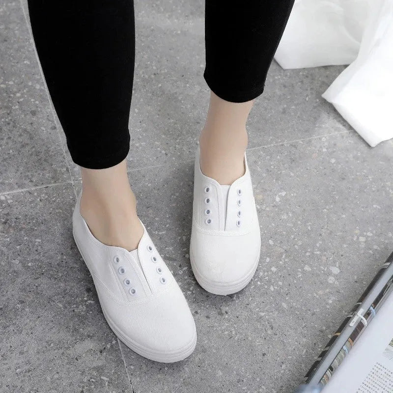 A pair of low-top casual canvas shoes in a flat style, shown in a choice of colours including black, white, grey, and pink.