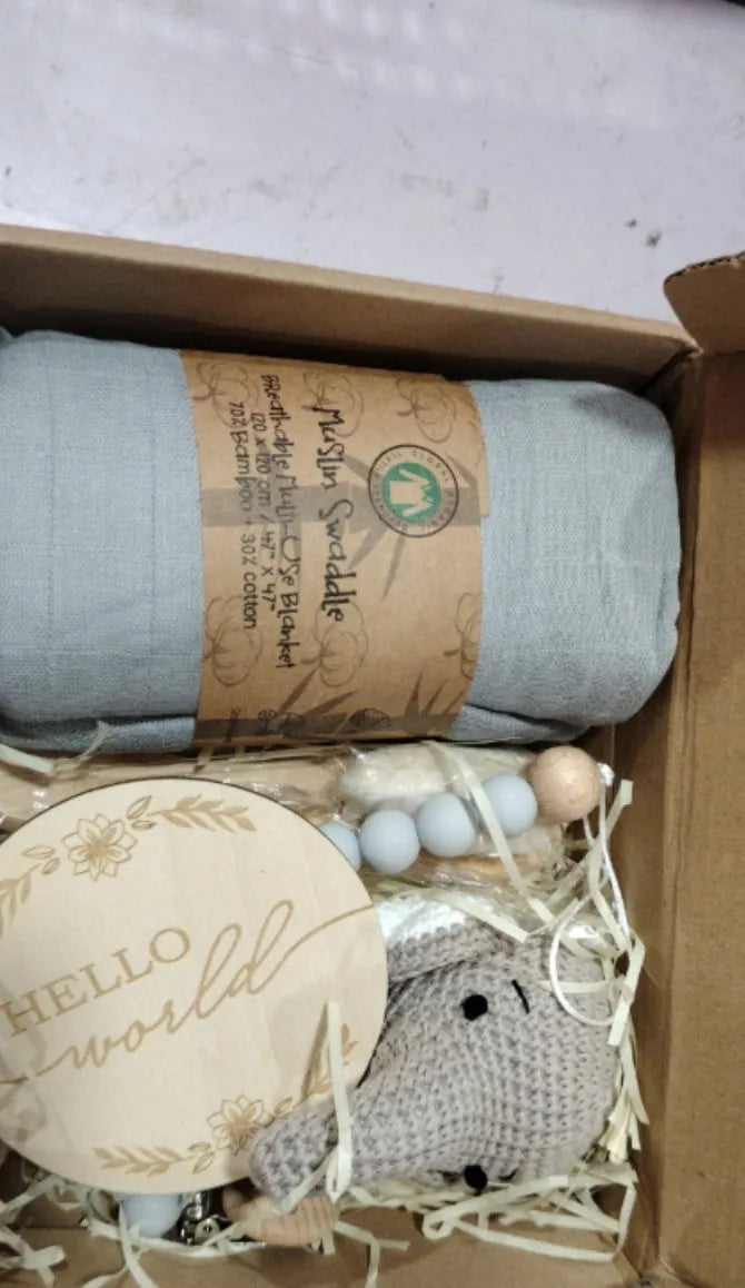 Baby teething toy gift set showing gauze blanket, wooden bell, gum teether, tire brush, and milestone on white background