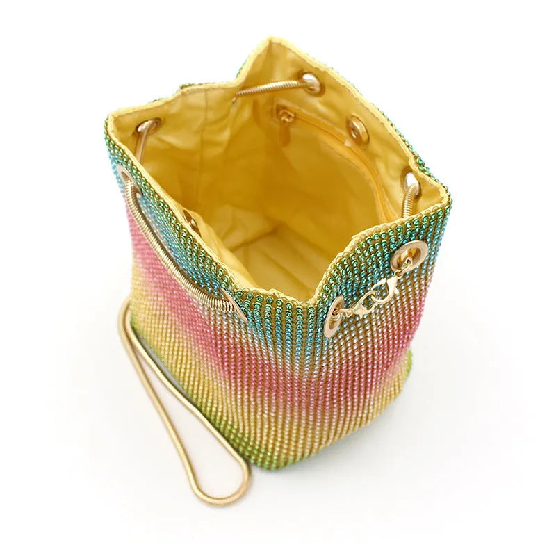 Rainbow coloured soft bucket handbag covered entirely in sparkling rhinestones with a top handle.