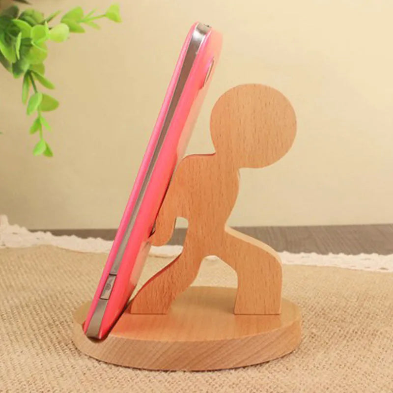 Solid beech wood mobile phone stand with a resin cow figurine and a slot for holding coins on a wooden desk.