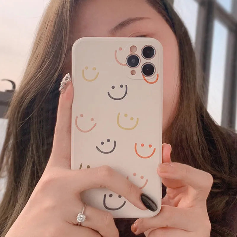 Simple silicone TPU iPhone case with a painted smiley face design on a solid colour background.