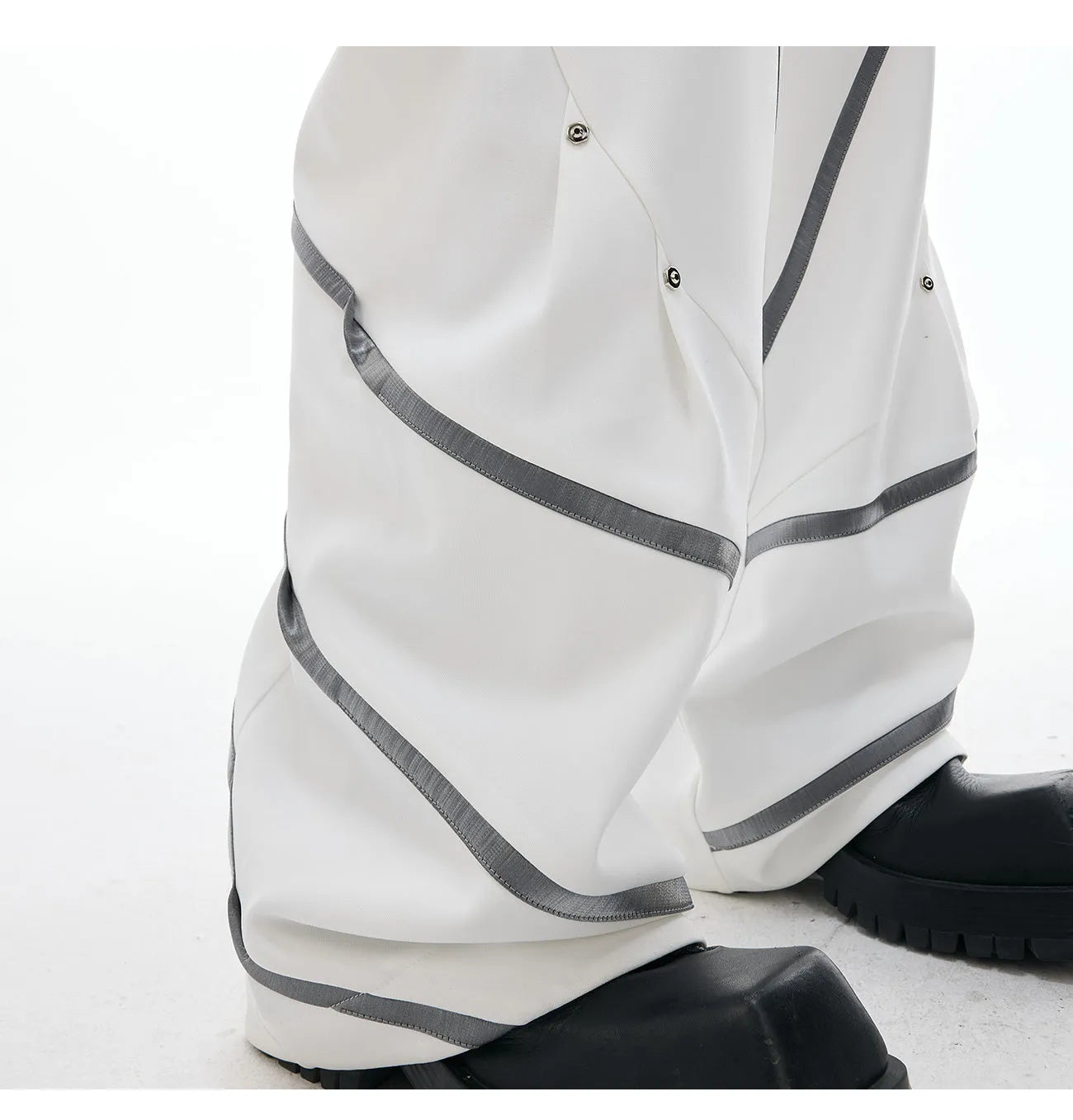 Men's black and white polyester trousers with 3D cutting, metal rivet stripes, and pleated front.
