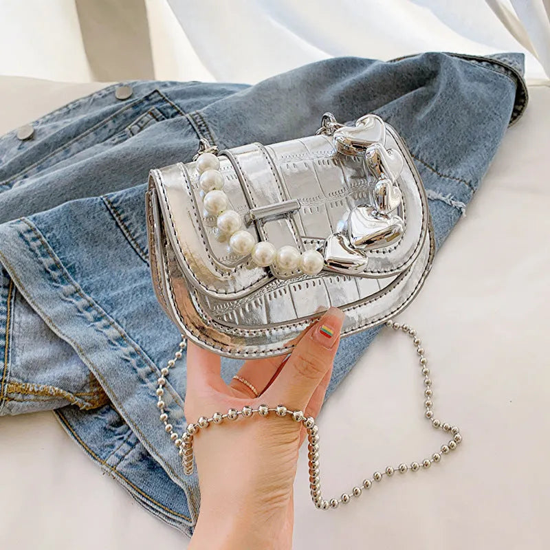 Silver women's PU leather mini tote saddle crossbody bag on a table.