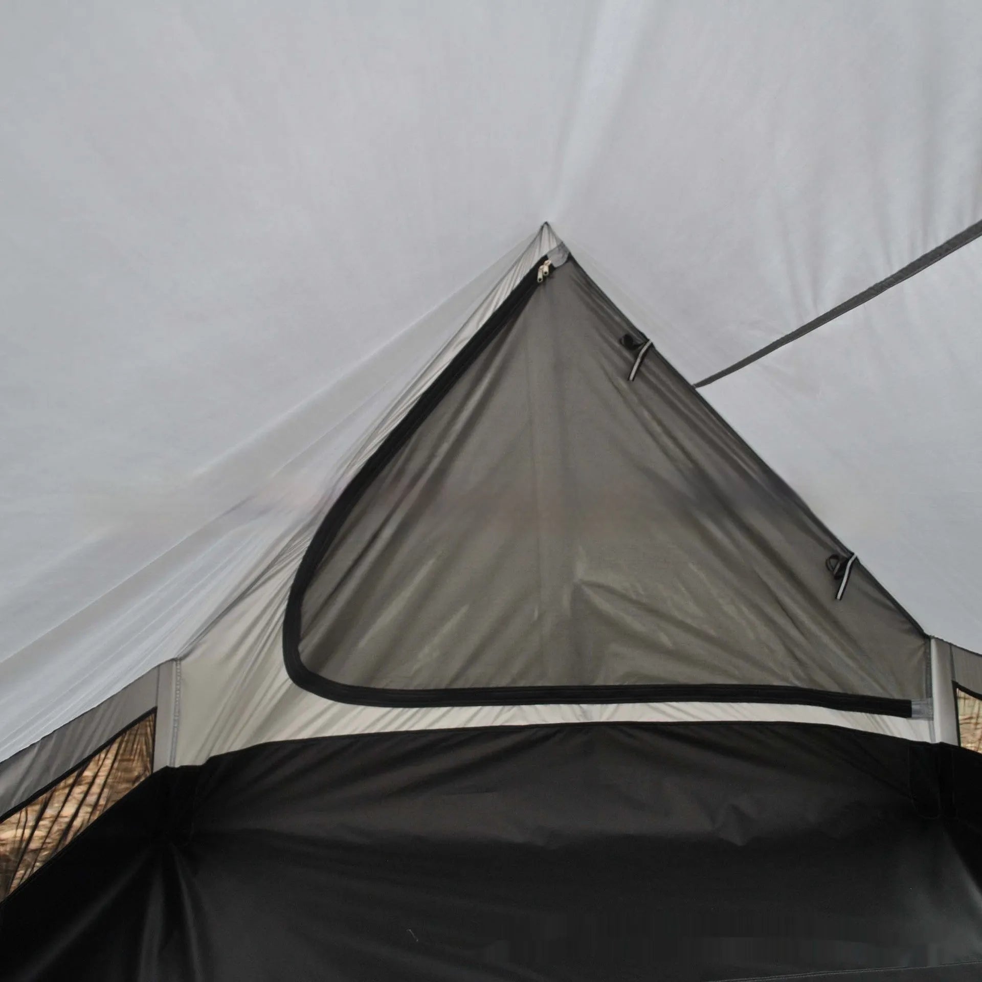 Brown A-Line pole-free cabin tent set up in a forest, showing its spacious interior for 2-3 people.