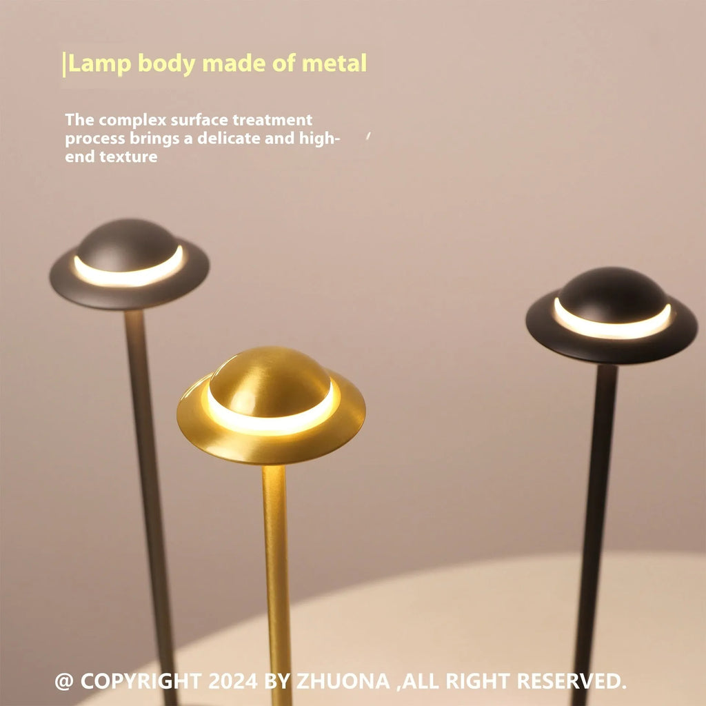 Modern gold UFO-shaped metal desk lamp with touch-sensitive base on a wooden table.