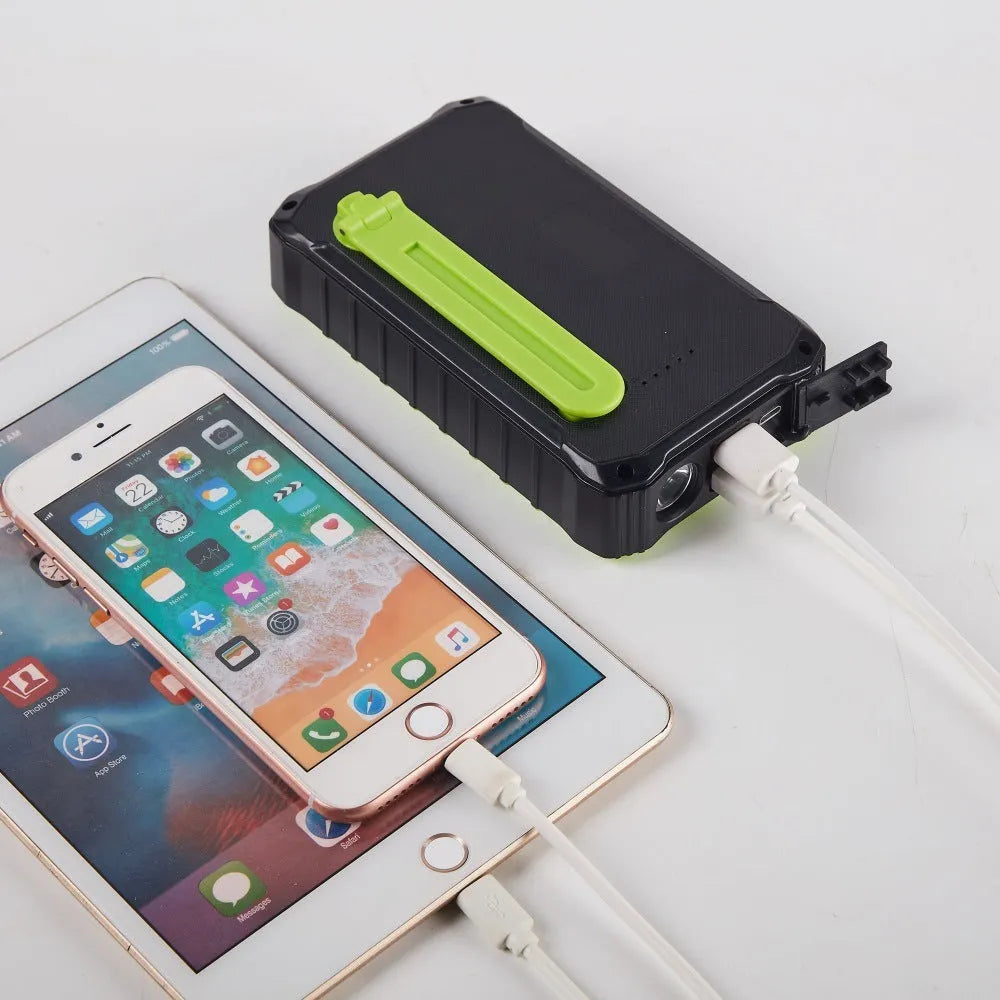 Orange and green portable solar hand crank power bank with USB ports and LED light.