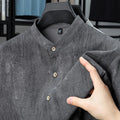 Man wearing a grey loose-fit linen blend cardigan shirt with a stand collar.