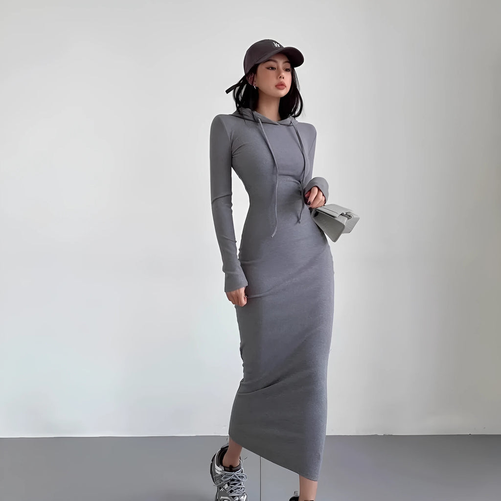 A woman modelling a grey hooded long-sleeve sheath dress with a high waist and over-the-knee length.