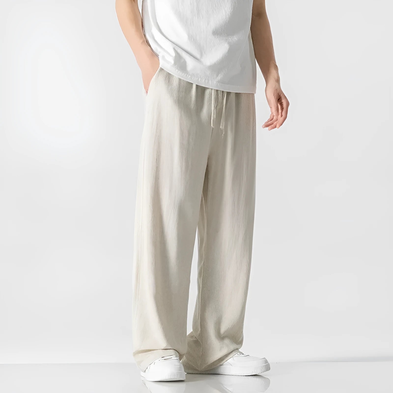 Man wearing beige bamboo fibre drawstring waist trousers with a cropped, straight leg.