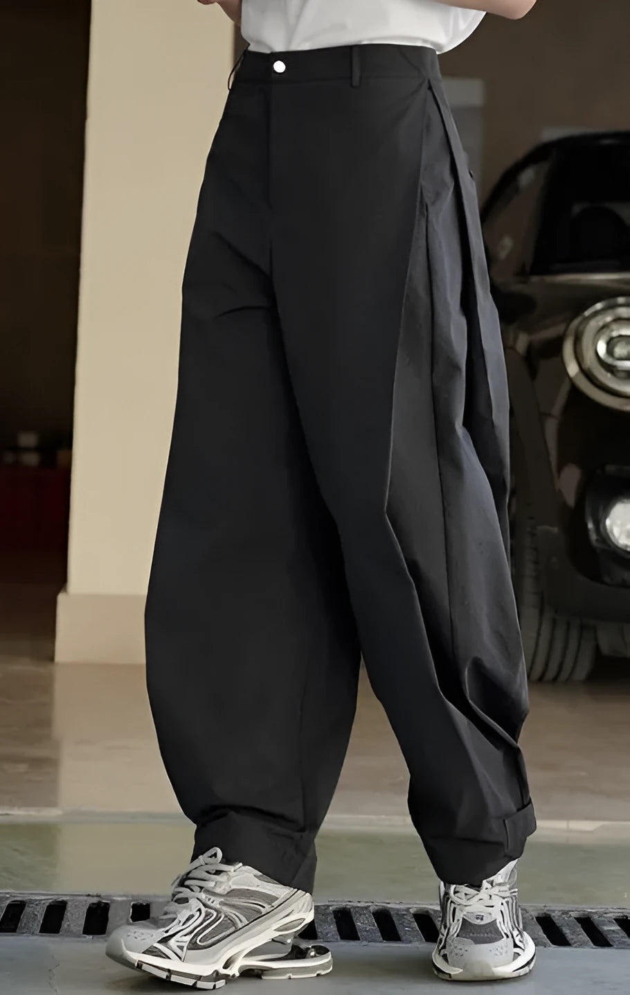 Black high-waisted women's trousers with a front pleat and loose wide-leg fit on a model.