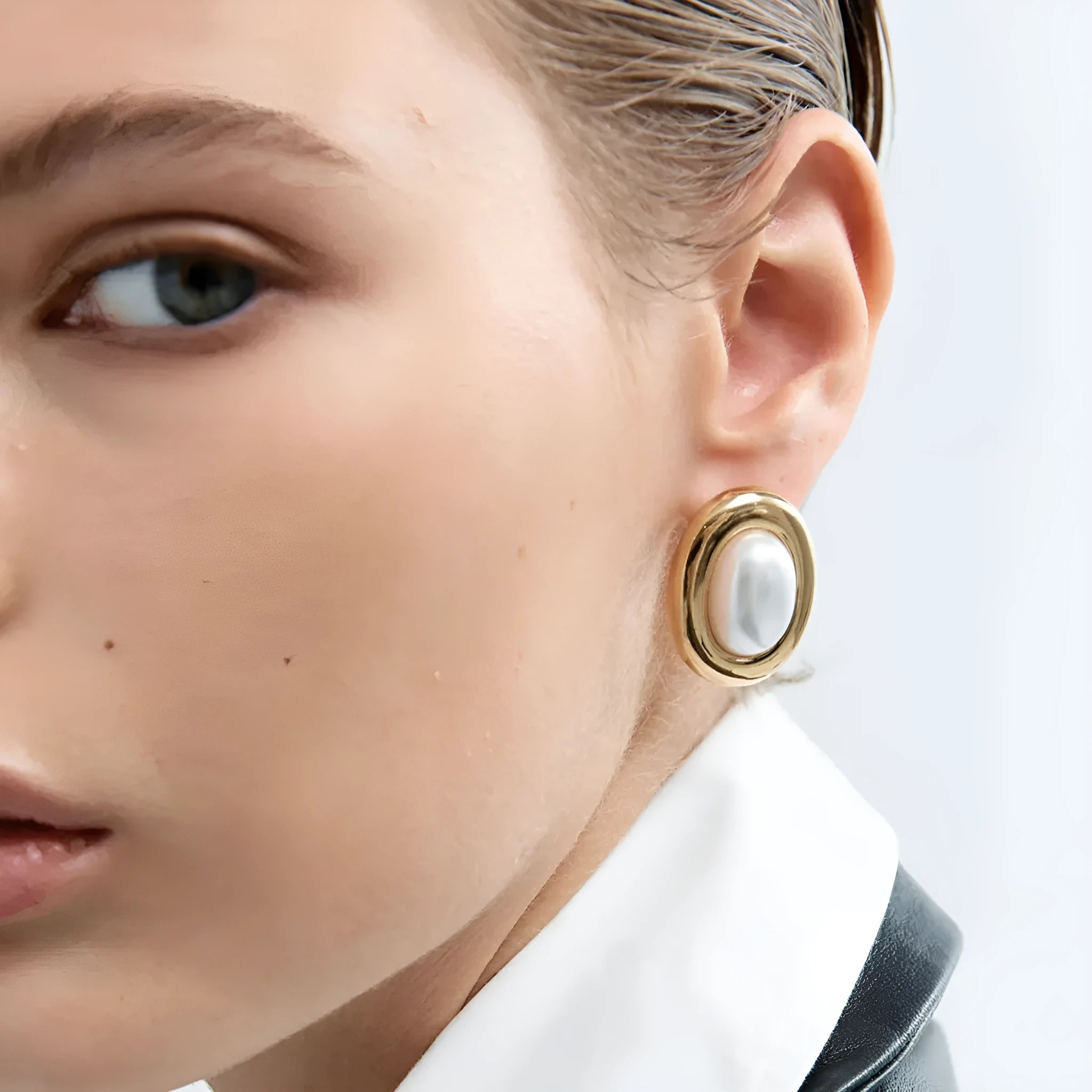 A pair of small stainless steel ear studs with a vintage-style pearl decoration on a silver-coloured base.