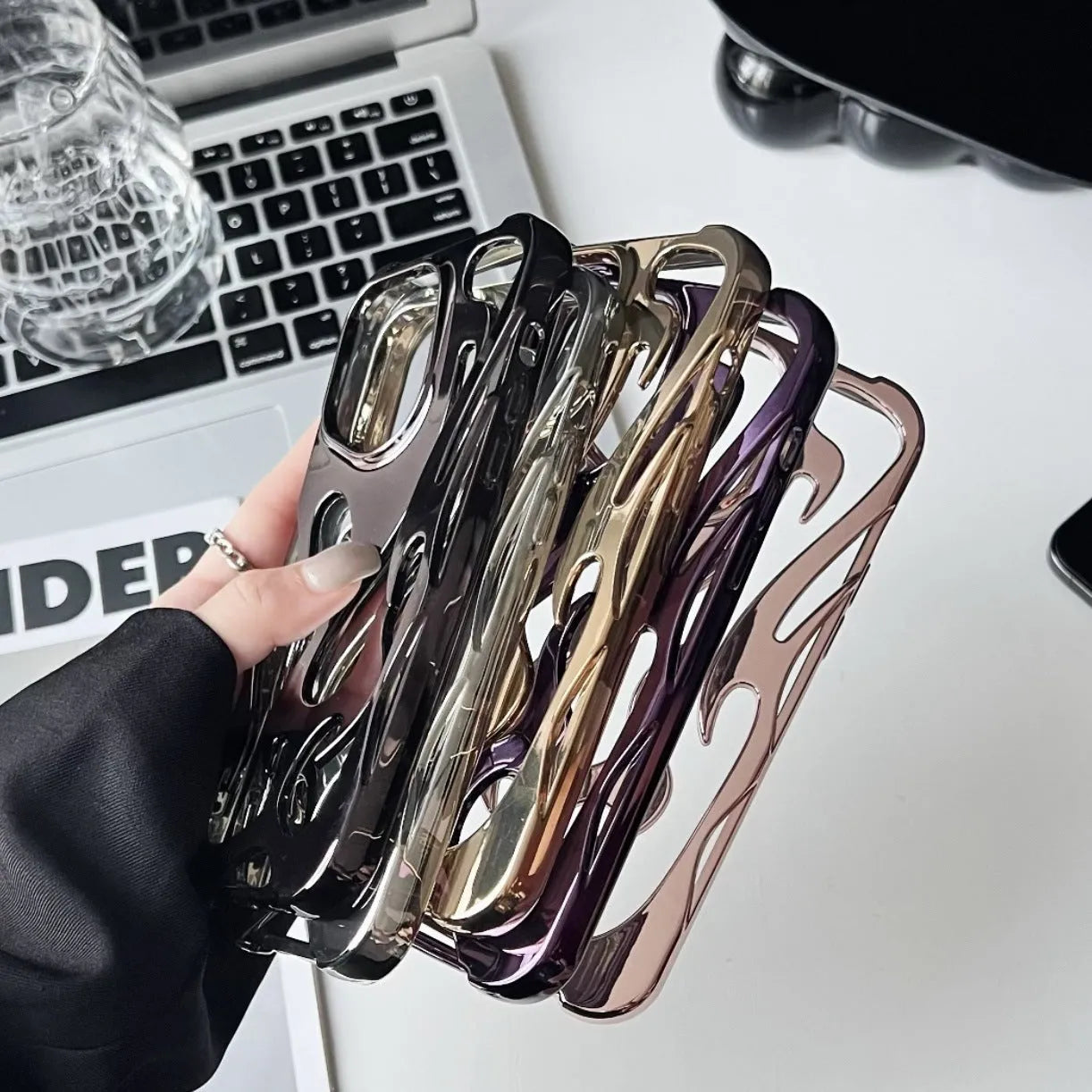 Electroplated hollow flame pattern iPhone case in silver, showing detailed cut-outs and metallic finish on a phone.