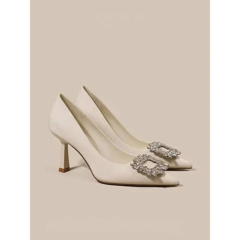 Women's creamy-white pointed toe stiletto high heels with a mid-height heel on a plain background.