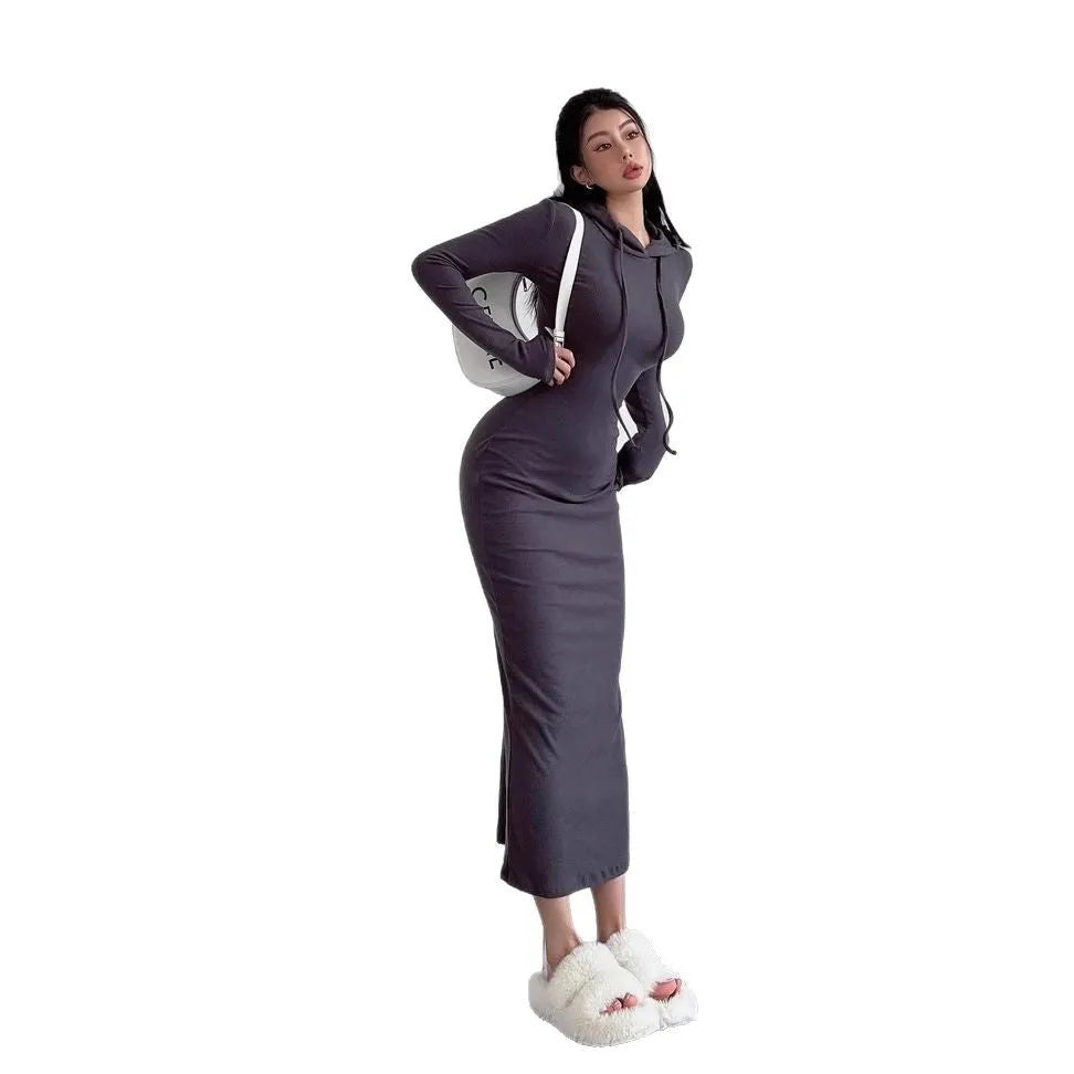 A woman modelling a grey hooded long-sleeve sheath dress with a high waist and over-the-knee length.