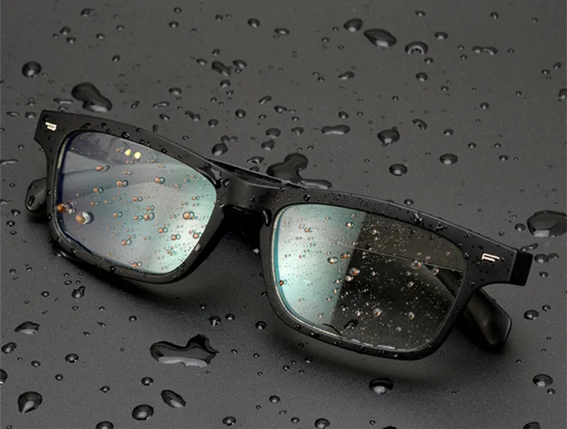 Black smart glasses with Bluetooth speakers and tinted UV-protection lenses on a table.